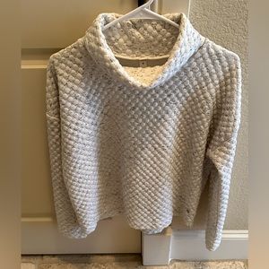 Apena cream with gray speckled, loose turtleneck sweater.